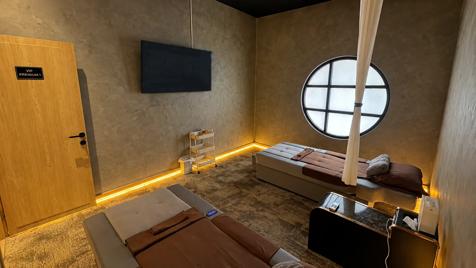 Ruang VIP Premium Senzu: dua bed perawatan, jendela bundar, dan TV di dinding