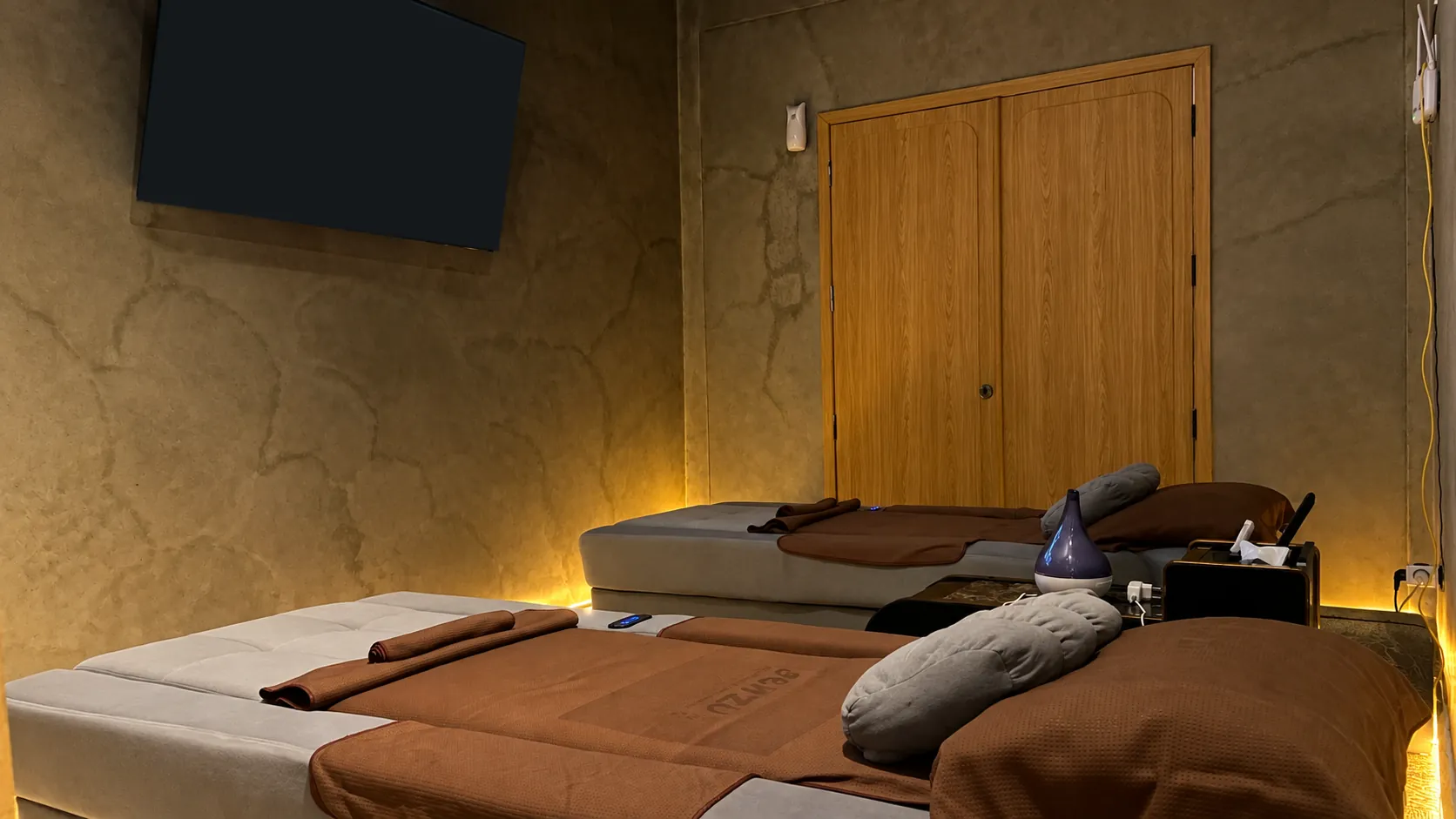 Ruang VIP Premium: dua bed dengan selimut bertuliskan Senzu dan TV besar di dinding