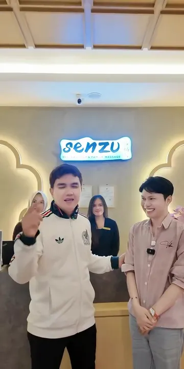 Aldi Taher dan rekannya di meja resepsionis Senzu Reflexology, di bawah papan nama Senzu yang menyala