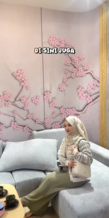 Alyssa duduk di sofa ruang tunggu bermotif sakura di Senzu Reflexology